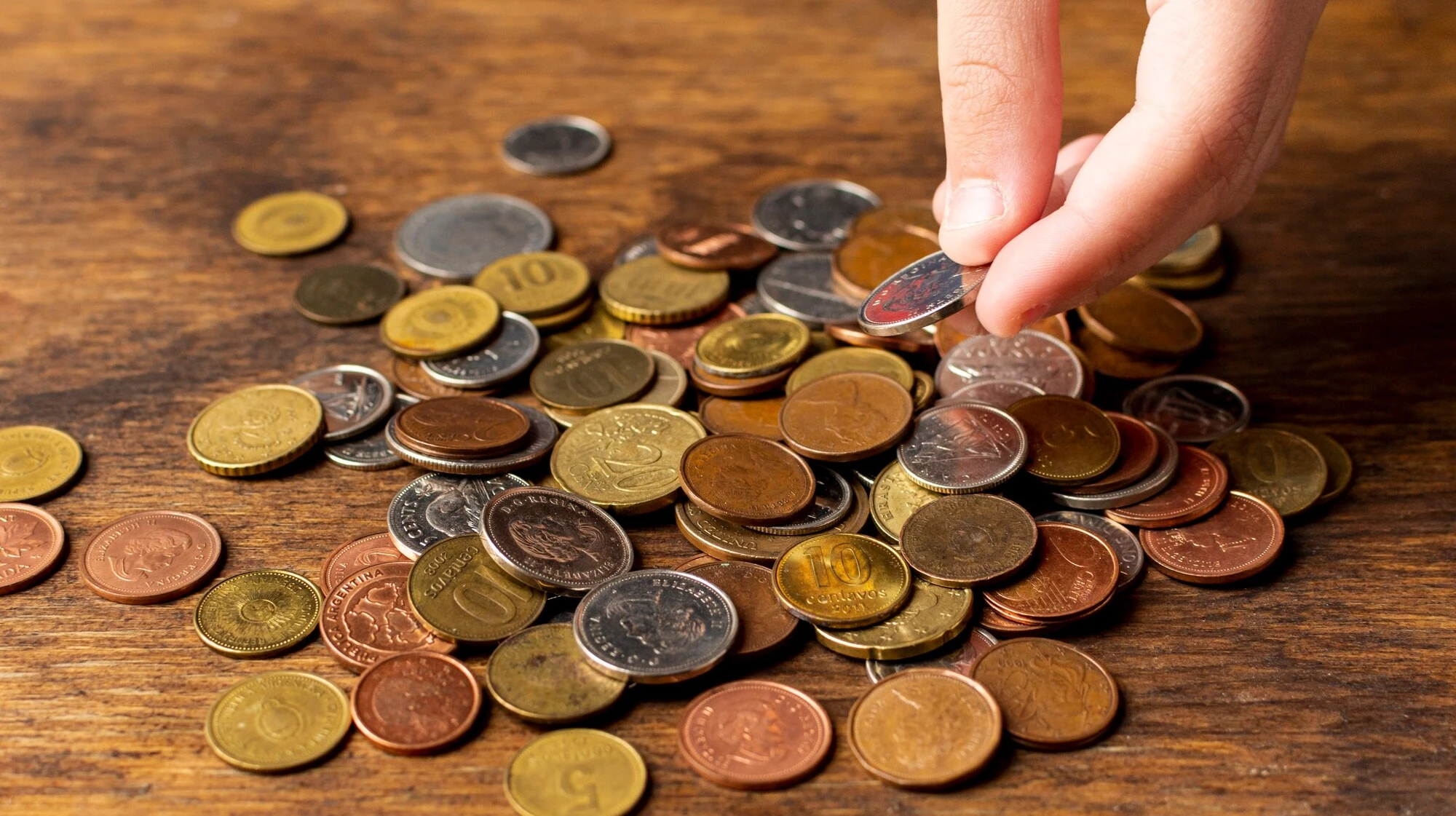 hand-holding-coin-from-pile-high